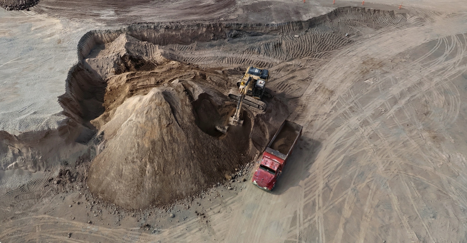 Excavadora cargando camión desde un acopio, vista aérea